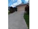 Long driveway leading to a tan house with an attached garage at 1810 Lawn S Ave, North Port, FL 34288