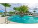 Resort-style swimming pool with palm trees, lounge chairs, and tropical landscaping under a partly cloudy sky at 18324 Rockport Pl, Lakewood Ranch, FL 34211