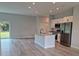 Open concept kitchen with island, stainless steel appliances, and grey vinyl flooring at 7137 Benson St, Englewood, FL 34224