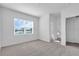 Sunlit bedroom with neutral carpet, a window overlooking the lake, and a glimpse into a bathroom at 17314 Alderwood Ln, Punta Gorda, FL 33982