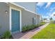Stylish blue front door with brick pathway, complemented by lush green landscaping and a clear blue sky at 17314 Alderwood Ln, Punta Gorda, FL 33982