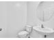Clean, all white powder room includes a toilet, modern sink, and round mirror at 17326 Alderwood Ln, Punta Gorda, FL 33982