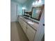 Bright bathroom featuring double sinks, granite counters, wood shelves, and wood-framed mirrors at 2633 Daisy Dr, North Port, FL 34289