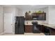 This kitchen features a black refrigerator and stove, with dark cabinetry and light countertops at 12843 Buffalo Run Dr, Gibsonton, FL 33534