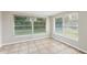 Bright bedroom featuring tile floors, neutral walls, and natural light from two large windows at 10226 Willow Dr, Port Richey, FL 34668