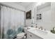 Well-lit bathroom with white cabinets, modern fixtures, a patterned shower curtain, and white walls at 7940 Fashion Loop, New Port Richey, FL 34654