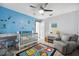 Nicely-decorated bedroom featuring cartoon wall decor, crib, comfortable chair, and tile flooring at 7940 Fashion Loop, New Port Richey, FL 34654