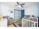 Cozy bedroom with a ceiling fan, cartoon-themed rug, comfortable chair and white crib at 7940 Fashion Loop, New Port Richey, FL 34654