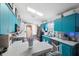 Modern kitchen featuring teal cabinets, granite countertops, and an island at 7940 Fashion Loop, New Port Richey, FL 34654