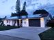 House exterior at dusk featuring a solar panel roof, gray garage door, and landscape lighting at 751 Nantucket Rd, Venice, FL 34293