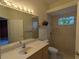 Bathroom featuring a large mirror, vanity, toilet, and shower, blending functionality with simple design elements at 23713 Acorn Hill Dr, Lutz, FL 33559