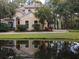 Charming two-story home featuring a perfectly manicured lawn and is perfectly reflected in a pond at 23713 Acorn Hill Dr, Lutz, FL 33559