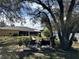 Relaxing backyard patio with seating area under large shade trees at 20102 Lorenzo Ave, Port Charlotte, FL 33952