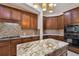 A modern kitchen shows brown cabinets, backsplash, granite countertops, stainless appliances, and an island with pendant lights at 11909 Mandevilla Ct, Tampa, FL 33626