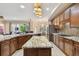 Open kitchen featuring island, granite countertops, wooden cabinetry, and a view towards the living area at 11909 Mandevilla Ct, Tampa, FL 33626