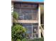 View of the home's exterior featuring a screened balcony with outdoor seating, with green foliage visible at 642 Bird Bay E Dr # 205, Venice, FL 34285