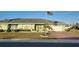 Charming one-story home with a green facade, mature landscaping, and a brick-paved driveway at 906 Bluewater Dr, Sun City Center, FL 33573