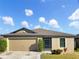 Tan one-story house with a two-car garage and landscaping at 922 Wynnmere Walk Ave, Ruskin, FL 33570