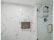 Close-up of a glass shower with marble tile, and a bronze finish shower head at 2413 Bayshore Blvd # 1404, Tampa, FL 33629