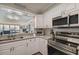 Well-lit kitchen showcasing granite countertops, stainless steel appliances, white cabinets, and a pass-through to the living room at 2413 Bayshore Blvd # 1404, Tampa, FL 33629