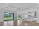Open-concept living space with hardwood floors, large glass doors to the lanai, and views of the lake at 2515 Wise River Lane, Zephyrhills, FL 33539