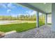 Covered patio with brick flooring overlooking a large grassy area and a tranquil lake at 2515 Wise River Lane, Zephyrhills, FL 33539