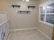 An empty room with neutral colored tile, a window with shutters, and floating shelving on the wall at 903 Pinellas Bayway S # 302, Tierra Verde, FL 33715