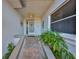 Charming covered front porch with neutral colored tile, complemented by decorative wall art and manicured plants at 903 Pinellas Bayway S # 302, Tierra Verde, FL 33715