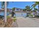 Townhome exterior showcasing a two-car garage, tile roof, and lush tropical landscaping at 903 Pinellas Bayway S # 302, Tierra Verde, FL 33715