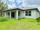 Home's backyard featuring sliding glass doors, covered porch, and green lawn at 1074 Kacerik St, North Port, FL 34288