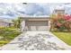 View of the two-car garage with flowering shrubbery on a sunny day at 13619 Twin Lakes Ln # 15, Tampa, FL 33618