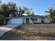 Charming one-story home with a front lawn, a white garage door and an arched front door at 21300 Washburn Ave, Port Charlotte, FL 33952