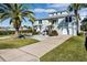 Two-story light green house with a large driveway, landscaping, and palm trees at 4049 Cobia Dr, Hernando Beach, FL 34607