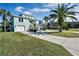 Two-story light green house with a large driveway, landscaping, and palm trees at 4049 Cobia Dr, Hernando Beach, FL 34607
