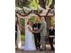 Couple exchanging vows under a floral wedding arch at 15625 State Road 62 St, Parrish, FL 34219