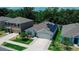 This home features a paved driveway, a two car garage, solar panels, and a lush green yard at 7729 Rosewood Garden Loop, Tampa, FL 33637