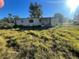 Mobile home with overgrown grass and boarded windows, in need of repairs at 6517 Mangrove Dr, Wesley Chapel, FL 33544