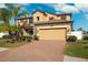 Two story house with tan exterior, red shutters, and a brick driveway at 1726 Cameron Court, Trinity, FL 34655
