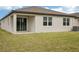 Backyard with sliding glass doors, windows, and a grassy lawn at 104 Runaway Field Ave, Nokomis, FL 34275