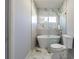 Elegant bathroom with a freestanding tub, marble tiling, and a modern shower, creating a spa-like experience at 6370 Conniewood Sq, New Port Richey, FL 34653