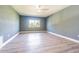 Bright bedroom with a ceiling fan, light blue walls, a window with trees, and wood floors at 6370 Conniewood Sq, New Port Richey, FL 34653