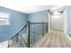 Upstairs hallway with wood floors and a modern metal railing leading to the bedrooms at 6370 Conniewood Sq, New Port Richey, FL 34653