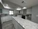 Modern kitchen boasting white cabinets, marble countertops, stainless appliances, and a large center island at 6370 Conniewood Sq, New Port Richey, FL 34653