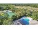 Aerial view showing a tennis court, pool, and golf course against a backdrop of lush trees at 5277 Epping Ln, Zephyrhills, FL 33541