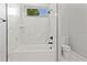 Bright bathroom with white marble tile, bathtub, shower, and toilet at 5277 Epping Ln, Zephyrhills, FL 33541