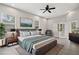 A modern bedroom with gray walls, a large bed, ceiling fan, wood-look floors, and a painting on the wall at 5277 Epping Ln, Zephyrhills, FL 33541