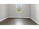 An empty bedroom with wood-look floors and a view of the trees outside the window at 5277 Epping Ln, Zephyrhills, FL 33541