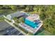Aerial shot of a large swimming pool with surrounding palm trees, tennis court, and parking at 5277 Epping Ln, Zephyrhills, FL 33541
