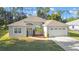 Beautiful light-colored home with a well-kept lawn, two-car garage and tastefully landscaped front yard at 5277 Epping Ln, Zephyrhills, FL 33541