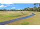 Picturesque golf course view with a paved cart path winding through lush green fairways under a sunny, blue sky at 5277 Epping Ln, Zephyrhills, FL 33541